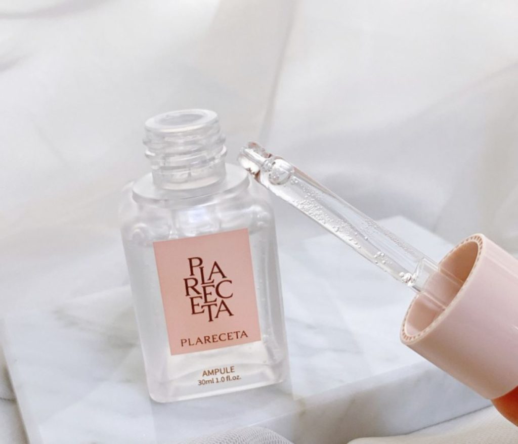 Close-up of PLARECETA Ampoule with dropper showing clear lightweight serum texture on marble background